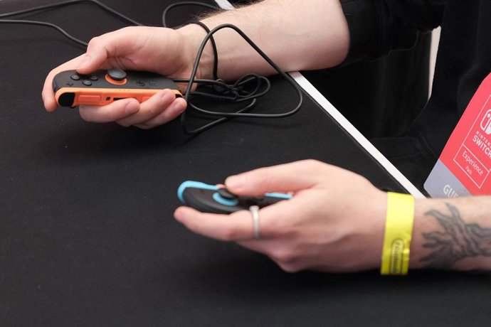 Archivo - Arquivo - 02 de abril de 2025, França, Paris: Um visitante segura os controles Joy-Con 2 durante o evento de lançamento do Nintendo Switch 2 no Grand Palais em Paris. O Switch 2 será o sucessor de seu antecessor, o terceiro console mais bem-suce