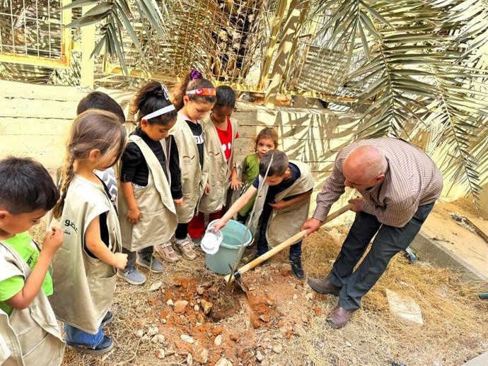 A group of children are planting a tree in the north of the West Bank as part of an initiative of the local Green Committee of their village