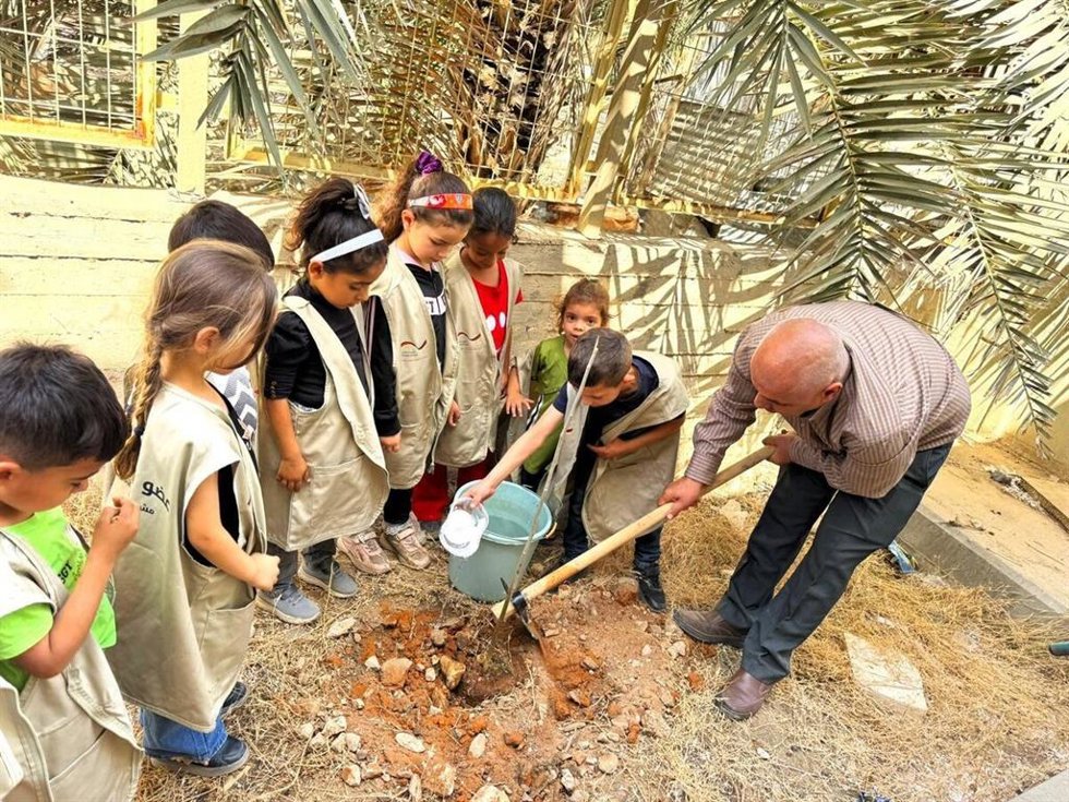A group of children are planting a tree in the north of the West Bank as part of an initiative of the local Green Committee of their village