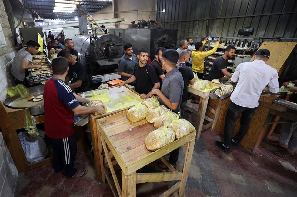 Trabajadores empaquetan pan para su distribución en la panadería del Programa Mundial de Alimentos (PMA) en Deir al Balá, en la Franja de Gaza  