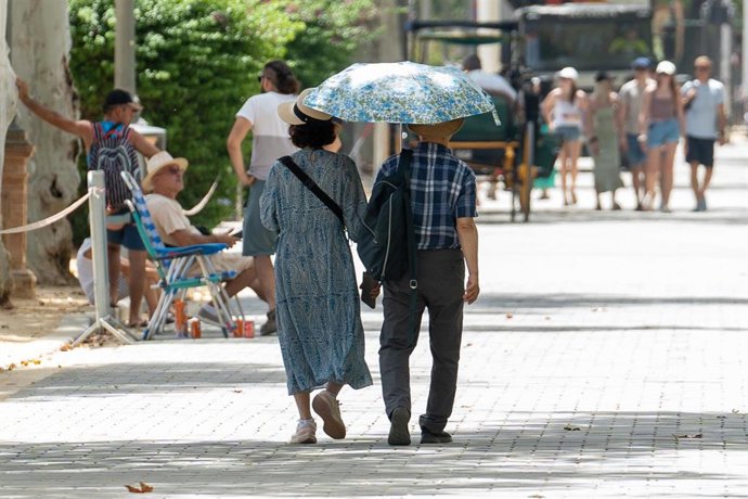 Archivo - Unos turistas pasean por la ciudad resguardados por un paraguas, a 19 de julio de 2024, en Sevilla, Andalucía (España). La primera ola de calor del verano pone en alerta a Sevilla por altas temperaturas, tanto en la campiña como en la sierra nor