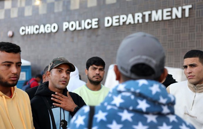 Archivo - Arquivo - 6 de outubro de 2023: Migrantes da Venezuela ouvem Brayan Lozano, de costas para a câmera, do lado de fora da delegacia do 1º Distrito do Departamento de Polícia de Chicago em 6 de outubro de 2023. Lozano, um solicitante de asilo da Co
