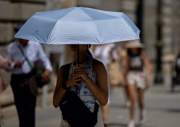 Archivo - Una mujer se resguarda del sol bajo un paraguas, a 18 de julio de 2024, en Madrid (España). La primera ola de calor del verano pone hoy en aviso amarillo o naranja a casi toda España, con temperaturas que superarán los 40 grados en algunos punto