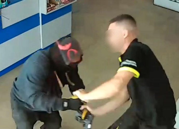 Um dos funcionários do posto de gasolina luta contra o assaltante.