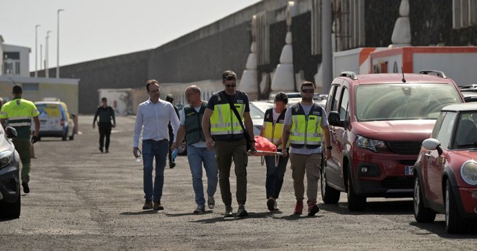 Agentes de Policía Nacional y la Guardia Civil llevan en la camilla a rescatan a uno de los migrantes que viajaban en el cayuco que ha volcado a su llegada al puerto de La Restinga