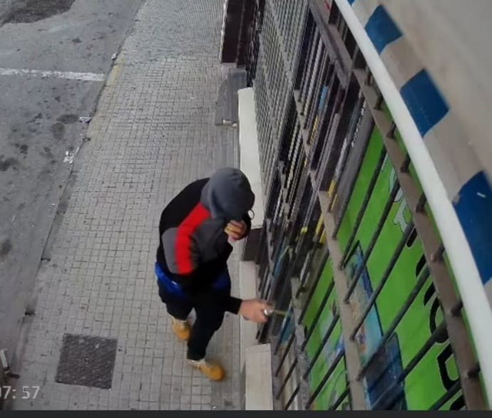 Una persona realizando una pintada de contenido racista en el negocio de un vecino de nacionalidad marroquí de Barbate