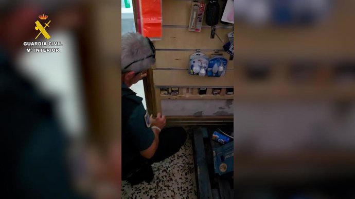 Un agente deja a la luz tabaco de contrabando oculto en el doble fondo de la pared de un bazar.