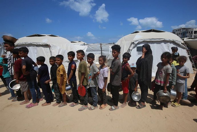 Niños palestinos hacen cola para coger comida.