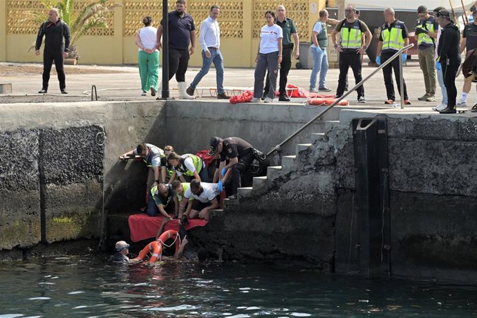 Agentes de Policía Nacional rescatan a uno de los migrantes que viajaba en un cayuco que ha volcado a su llegada al puerto de La Restinga