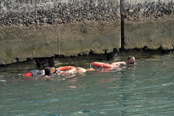 Agentes de Policía Nacional rescatan a los migrantes que viajaban en el cayuco que ha volcado a su llegada al puerto de La Restinga