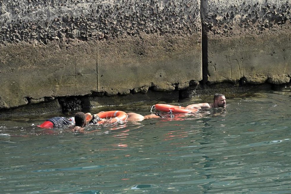 Agentes de Policía Nacional rescatan a los migrantes que viajaban en el cayuco que ha volcado a su llegada al puerto de La Restinga