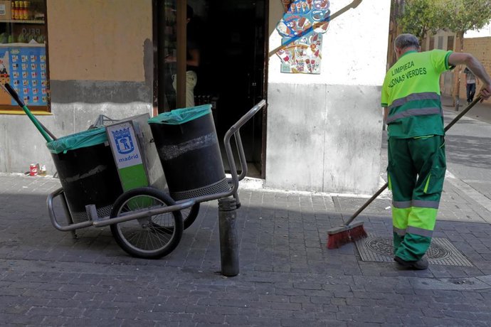 Archivo - Un barrendero del Ayuntamineto de Madrid, limpia en una calle del centro de la ciudad, junto a su carro de la limpieza.