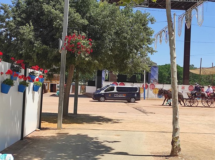 Um veículo da Polícia Nacional passa pelo recinto de feiras de El Arenal seguido por uma carruagem puxada por cavalos.