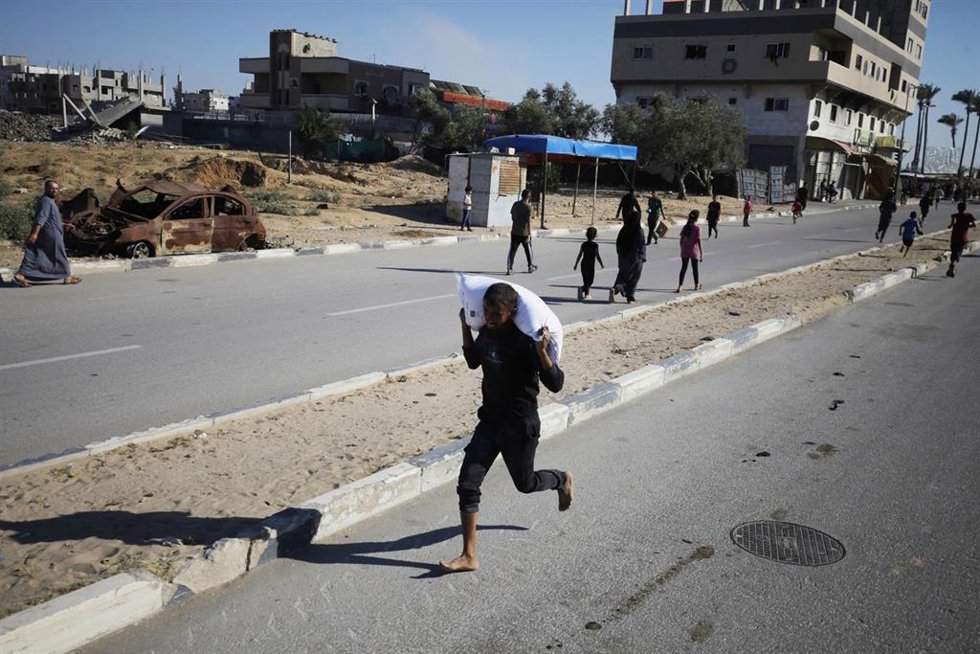 Un joven palestino corre con un saco de ayuda humanitaria en Deir al Balá, Franja de Gaza