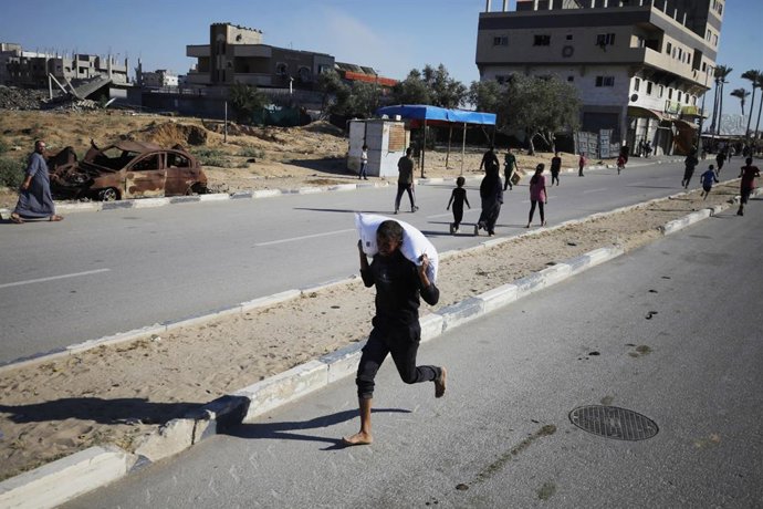 28 de maio de 2025, Deir El-Balah, Faixa de Gaza, Território Palestino: Palestinos deslocados carregam sacos de ajuda alimentar depois que pessoas invadiram um armazém do Programa Mundial de Alimentos em Deir el-Balah, no centro da Faixa de Gaza. As Naçõe