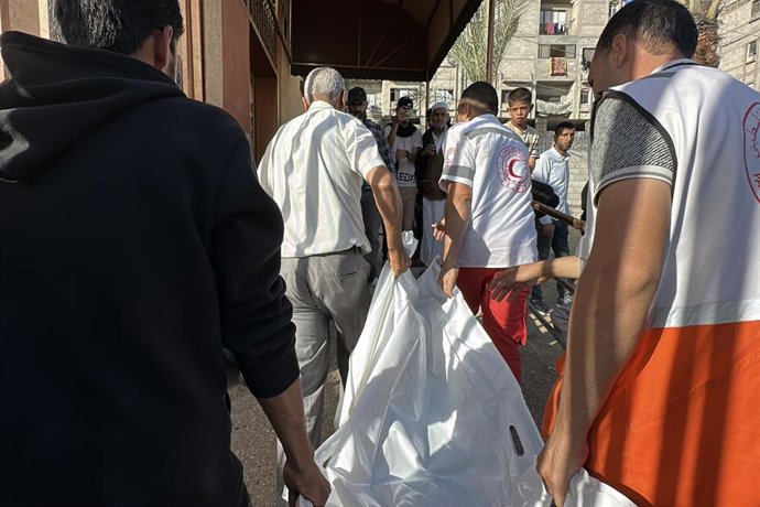 Miembros de la Media Luna Roja Palestina y familiares trasladan el cuerpo de una víctima en un ataque de Israel en Jan Yunis, sur de la Franja de Gaza