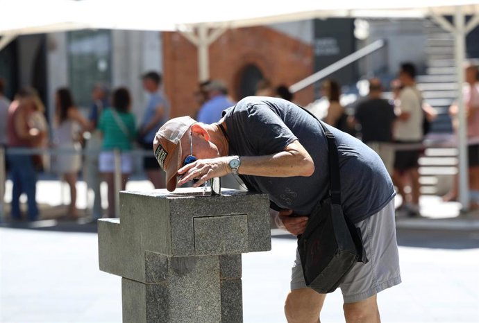 Archivo - Un hombre bebe agua de una fuente durante una jornada de calor.