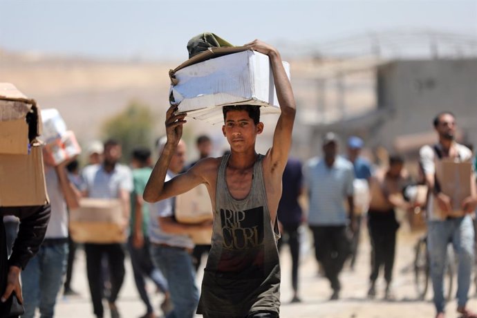 29 May 2025, Palestinian Territories, Bureij: Palestinians walk with aid supplies which they received from the US-backed Gaza Humanitarian Foundation, in Al-Bureij. Photo: Moiz Salhi/APA Images via ZUMA Press Wire/dpa