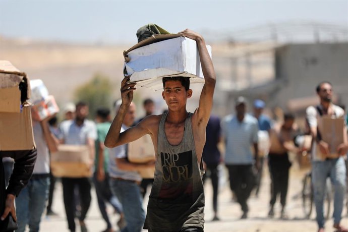 29 de maio de 2025, Territórios Palestinos, Bureij: Palestinos caminham com suprimentos de ajuda que receberam da Gaza Humanitarian Foundation, apoiada pelos EUA, em Al-Bureij. Foto: Moiz Salhi/APA Images via ZUMA Press Wire/dpa