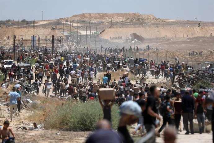 29 de maio de 2025, Territórios Palestinos, Bureij: Palestinos caminham com suprimentos de ajuda que receberam da Gaza Humanitarian Foundation, apoiada pelos EUA, em Al-Bureij. Foto: Moiz Salhi/APA Images via ZUMA Press Wire/dpa