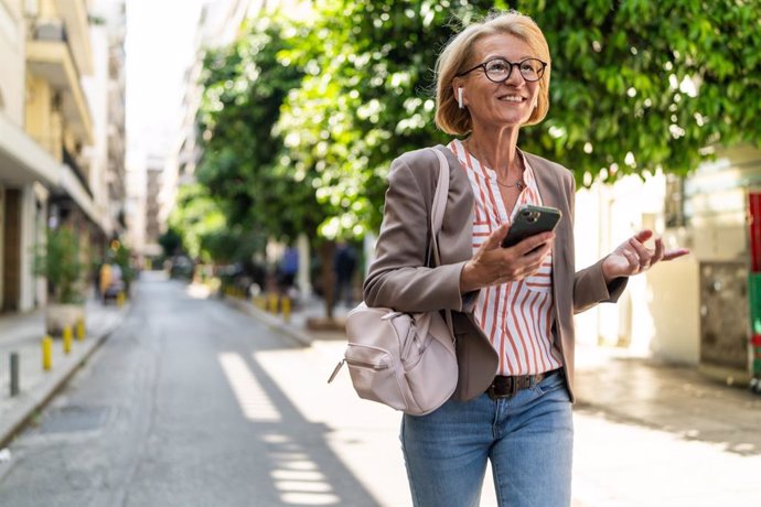 Archivo - Mujer andando por la calle mientras habla por el móvil.