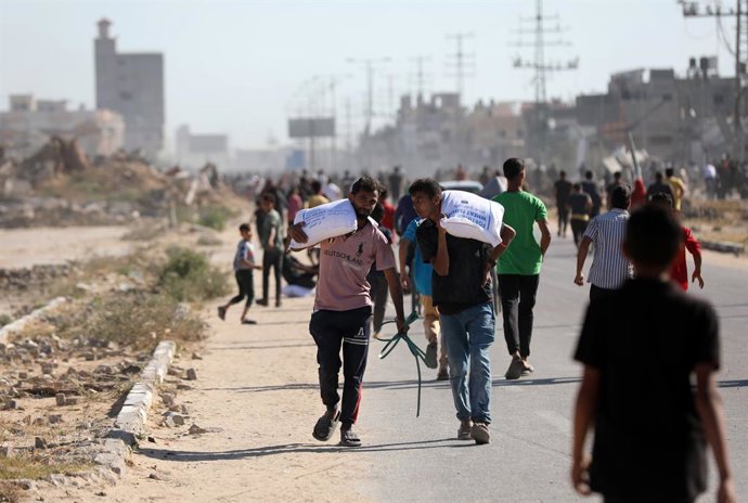 28 de maio de 2025, Deir El-Balah, Faixa de Gaza, Território Palestino: Palestinos deslocados transportam sacos de ajuda alimentar depois que pessoas invadiram um armazém do Programa Mundial de Alimentos em Deir el-Balah, no centro da Faixa de Gaza, em 28