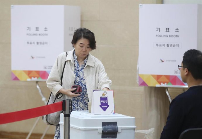 Una mujer deposita su voto en un urna en un centro electoral de Corea del Sur.