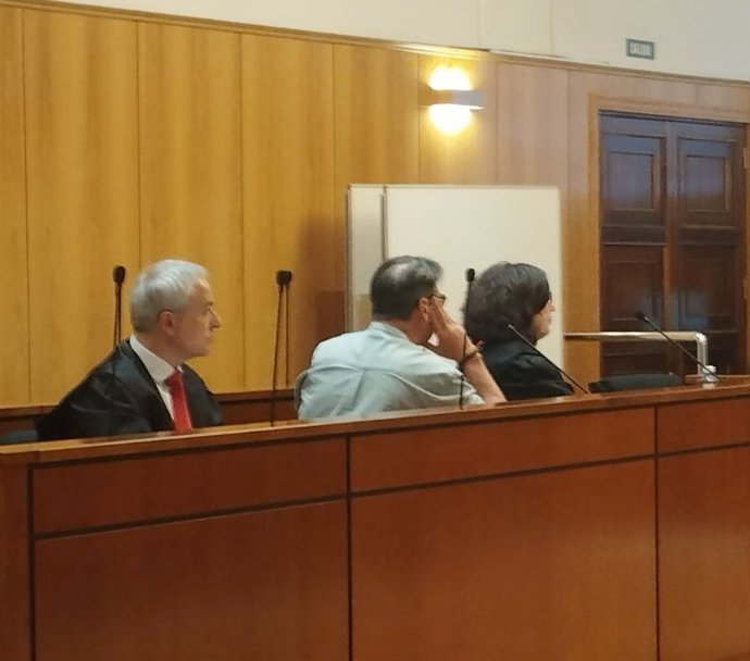 El agente de seguros condenado, en medio de espaldas entre sus abogados.