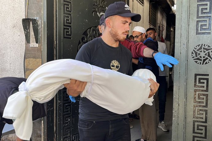 29 de maio de 2025, Territórios Palestinos, Jabalia: Um homem segura o corpo de uma criança morta por Israel após o ataque israelense a Jabalia, no norte da Faixa de Gaza. Foto: Hadi Daoud/APA Images via ZUMA Press Wire/dpa