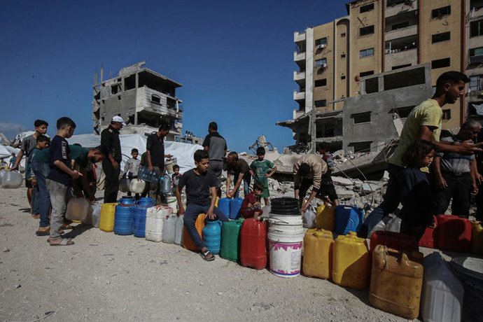 3 de junho de 2025, Cidade de Gaza, Faixa de Gaza, Território Palestino: Palestinos carregam galões cheios de água distribuídos por um caminhão-tanque, na cidade de Gaza, em 3 de junho de 2025. Os palestinos estão enfrentando dificuldades para ter acesso 