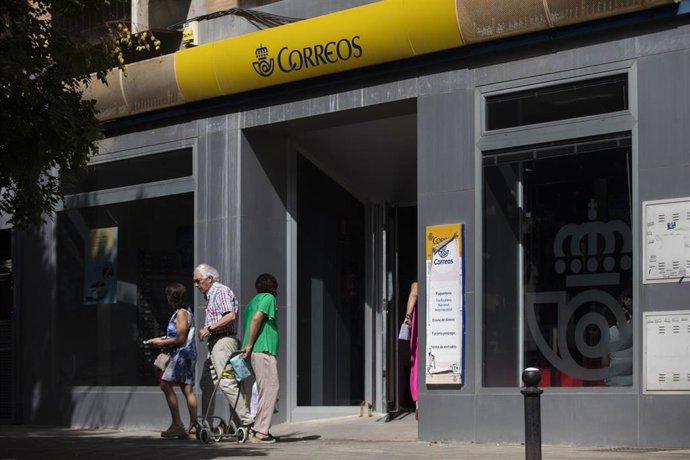 Archivo - Una persona entra en una oficina de correos.