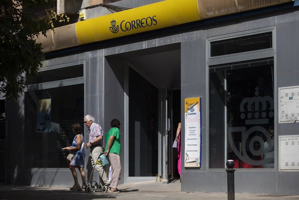 Archivo - Una persona entra en una oficina de correos.
