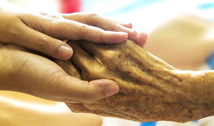 Una enfermera estrecha la mano de una paciente.