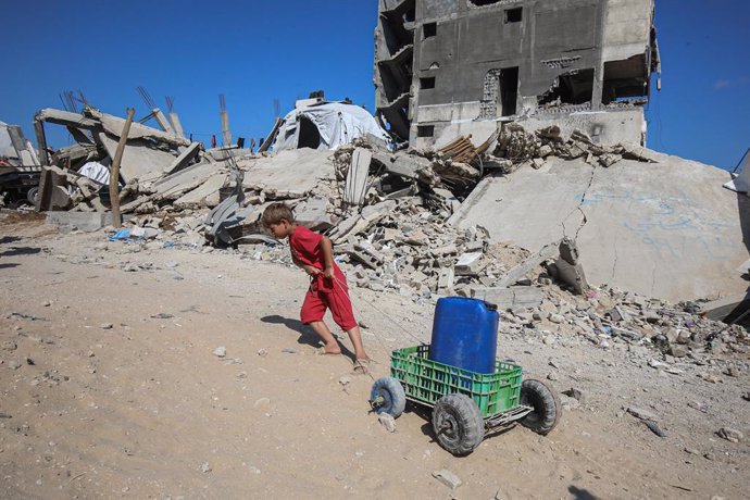 03 June 2025, Palestinian Territories, Gaza: A Palestinian child pulls jerry cans filled with water distributed by a water tanker. Palestinians are facing difficulties in accessing water due to the ongoing Israeli attacks on the Gaza Strip and the Israeli