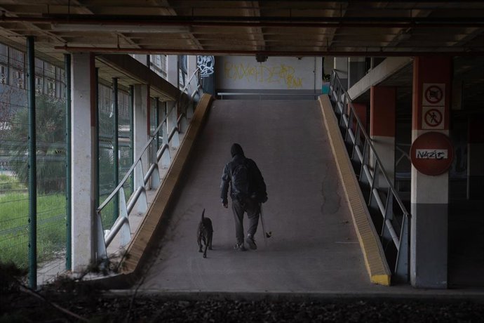 Archivo - Una persona con un perro en un parking del Aeropuerto de Barcelona.