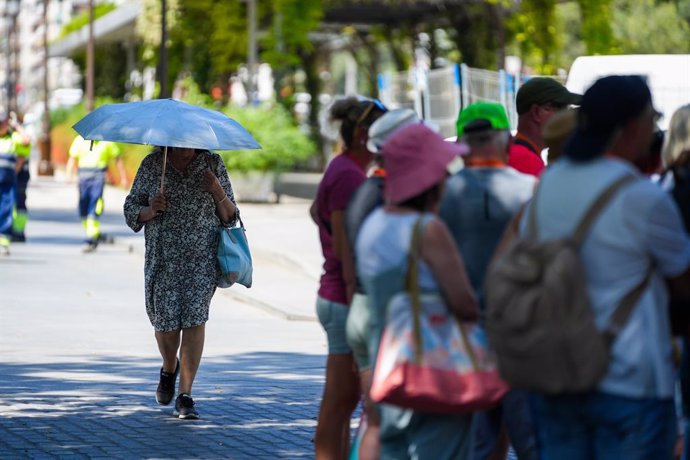 Una mujer con una sombrilla junto a un grupo de turistas. A 28 de mayo de 2025, en Sevilla (Andalucía, España).La Agencia Estatal de Meteorología (Aemet) ha activado para este miércoles el aviso amarillo por calor en diversas zonas de Córdoba, Jaén y Sevi