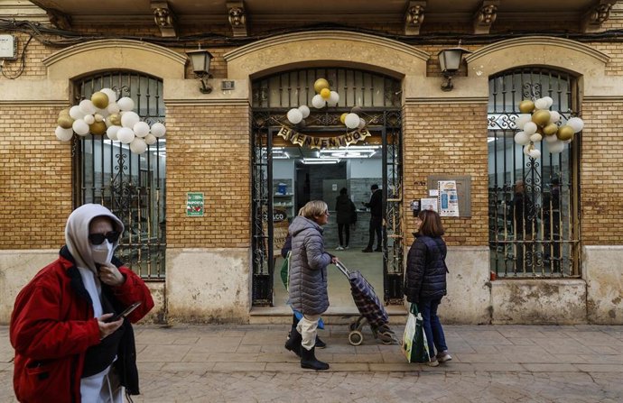 Archivo - Varias personas pasan por un comercio de Paiporta (archivo)