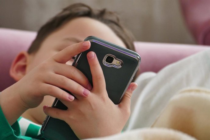 Archivo - Un niño usando un teléfono móvil