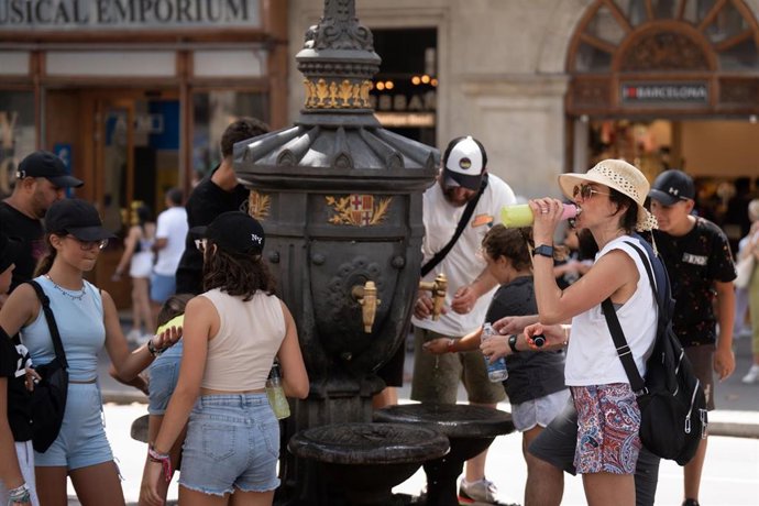 Archivo - Varias personas se refrescan y rellenan sus botellas de agua en la fuente de Canaletas, en una imagen de archivo