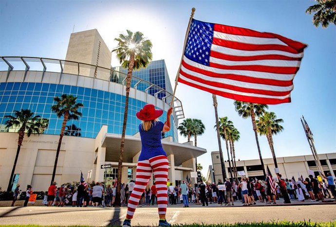 Archivo - 05 May 2020, US, Riverside: A woman waves the US national flag in front of the Riverside County Administration building during a demonstration against the Coronavirus exit restrictions. Photo: Watchara Phomicinda/Orange County Register via ZUMA/