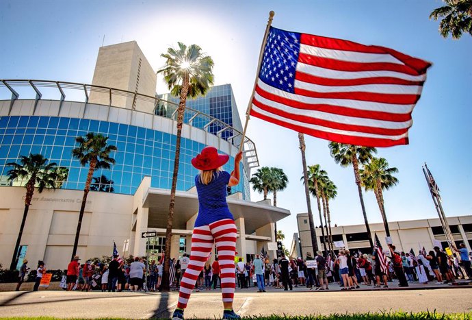 Archivo - 05 May 2020, US, Riverside: A woman waves the US national flag in front of the Riverside County Administration building during a demonstration against the Coronavirus exit restrictions. Photo: Watchara Phomicinda/Orange County Register via ZUMA/