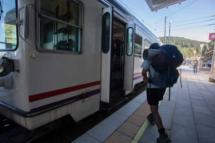 Un viajero con mochila sube al tren en la estación de Cotos, a 3 de septiembre de 2022, en Cotos, Comunidad de Madrid (España).