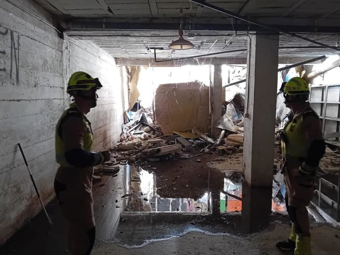 Bomberos en la planta del edificio desalojado  de la calle Zumalacárregui tras desprenderse una terraza interior y caer sobre el local, en un suceso en el que no ha habido que lamentar ninguna persona herida.