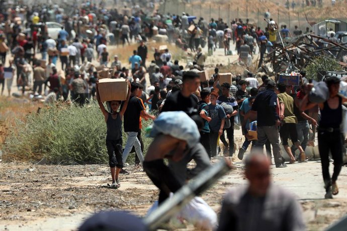 29 de maio de 2025, Territórios Palestinos, Bureij: Palestinos caminham com suprimentos de ajuda que receberam da Gaza Humanitarian Foundation, apoiada pelos EUA, em Al-Bureij. Foto: Moiz Salhi/APA Images via ZUMA Press Wire/dpa