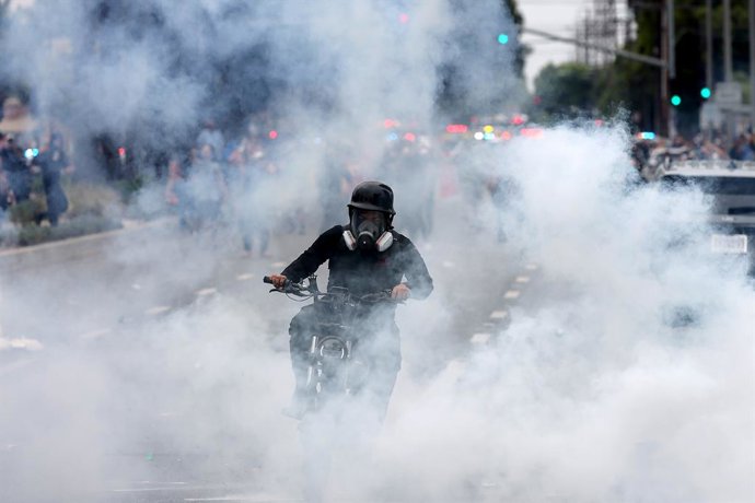 7 de junho de 2025, Compton, Califórnia, EUA: Um manifestante passa com uma motocicleta por gás de pimenta durante um protesto após uma batida do ICE em Paramount, Califórnia.
