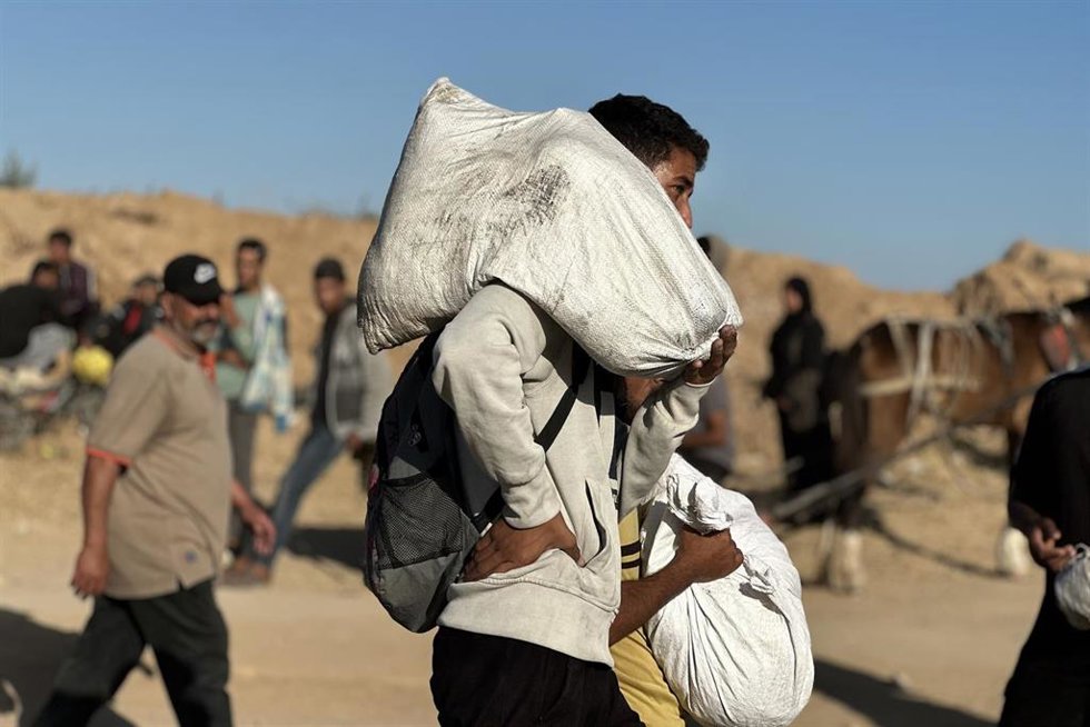 Palestinos transportan sacos de ayuda en ciudad de Gaza