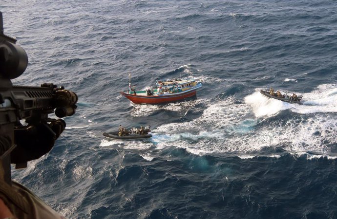 30 May 2025, ---: Undated handout photo issued by the Ministry of Defence shows crew holding their hands up in surrender as the Royal Marines close in. A Royal Navy frigate has seized drugs worth £30 million after stalking the drug-runner's boat for more 