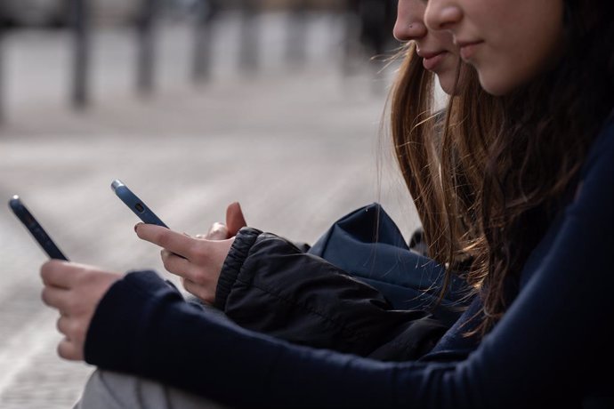 Archivo - Dos personas usan el teléfono móvil, a 1 de febrero de 2024, en Barcelona, Catalunya (España). El pasado 30 de enero el Govern aprobó las instrucciones que regulan el uso de los dispositivos móviles en las aulas de colegios e institutos, que se 