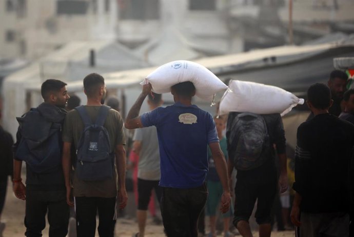 Palestinos cargan sacos de harina entregados por camiones de ayuda humanitaria en la ciudad de Gaza