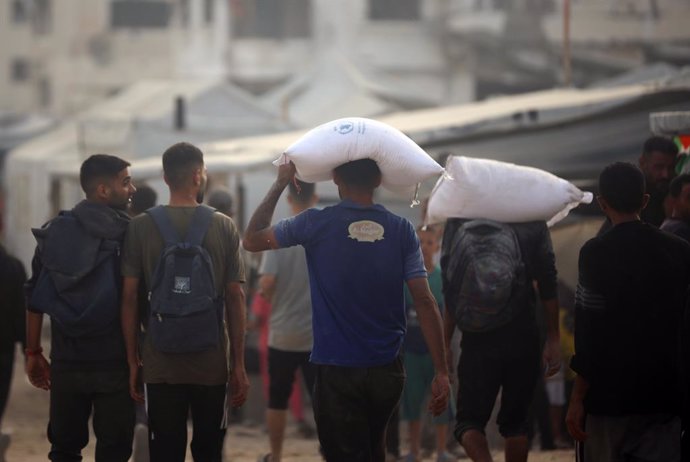 Palestinos cargan sacos de harina entregados por camiones de ayuda humanitaria en la ciudad de Gaza